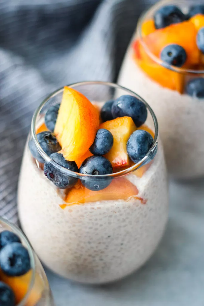 chia seed pudding topped with peaches and blueberries in glass jar