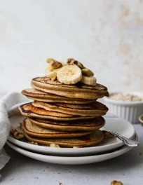 straight on closeup photo of a stack of banana oat pancakes on white plates