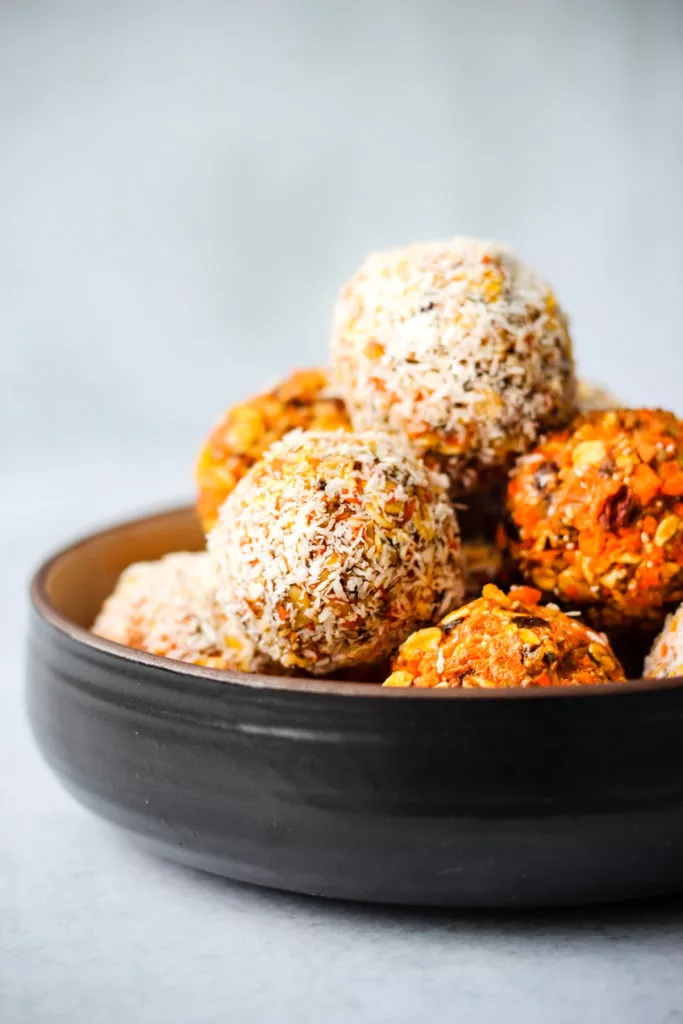 healthy no bake carrot cake energy bites stacked in a black bowl