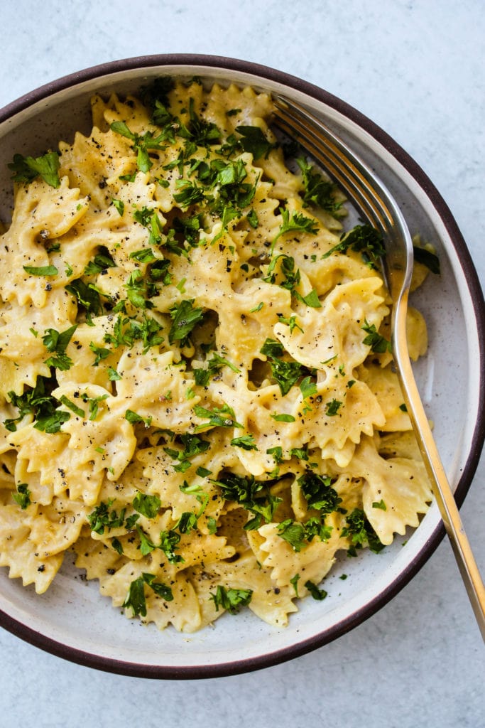 bowtie pasta tossed in miso tahini sauce and chopped parsley in bowl
