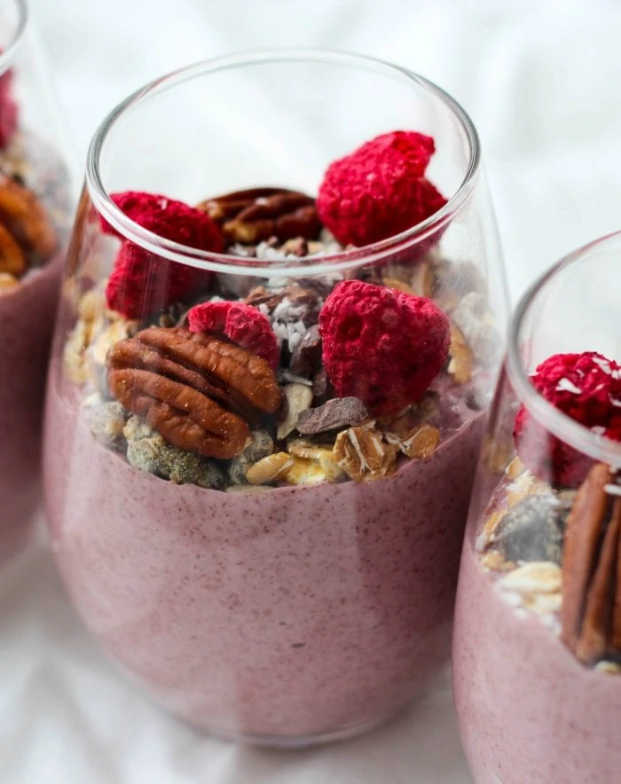 blended raspberry chia seed pudding topped with muesli, nuts, and seeds