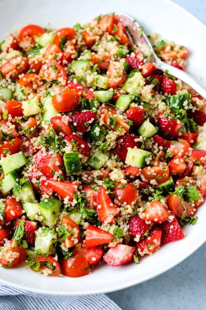Side angle photo of large white bowl with strawberry quinoa salad inside.