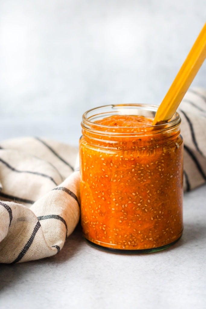 apricot chia jam in a glass jar with gold knife and stripped towel