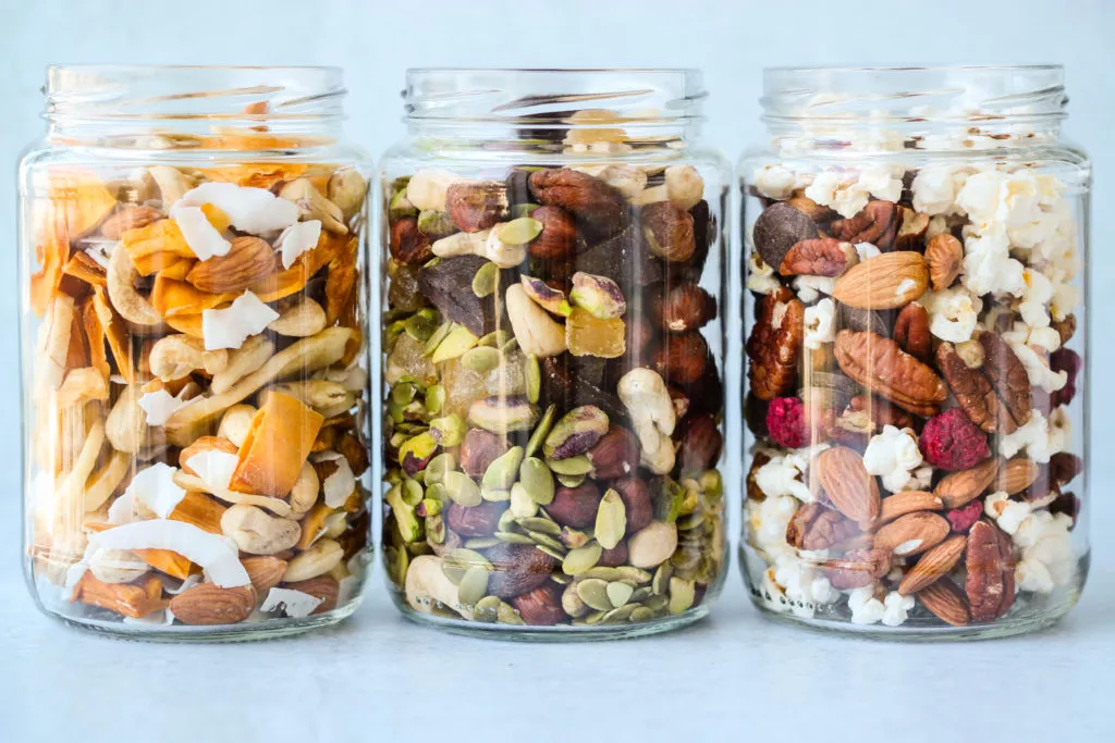 three glass jars with different homemade trail mix ingredient combinations