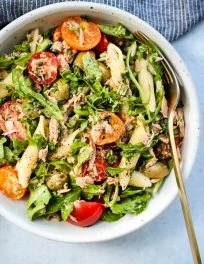 healthy tuna pasta salad with olives, tomatoes, arugula, and herbs