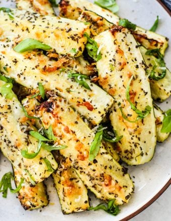 roasted zucchini with parmesan and basil on white plate