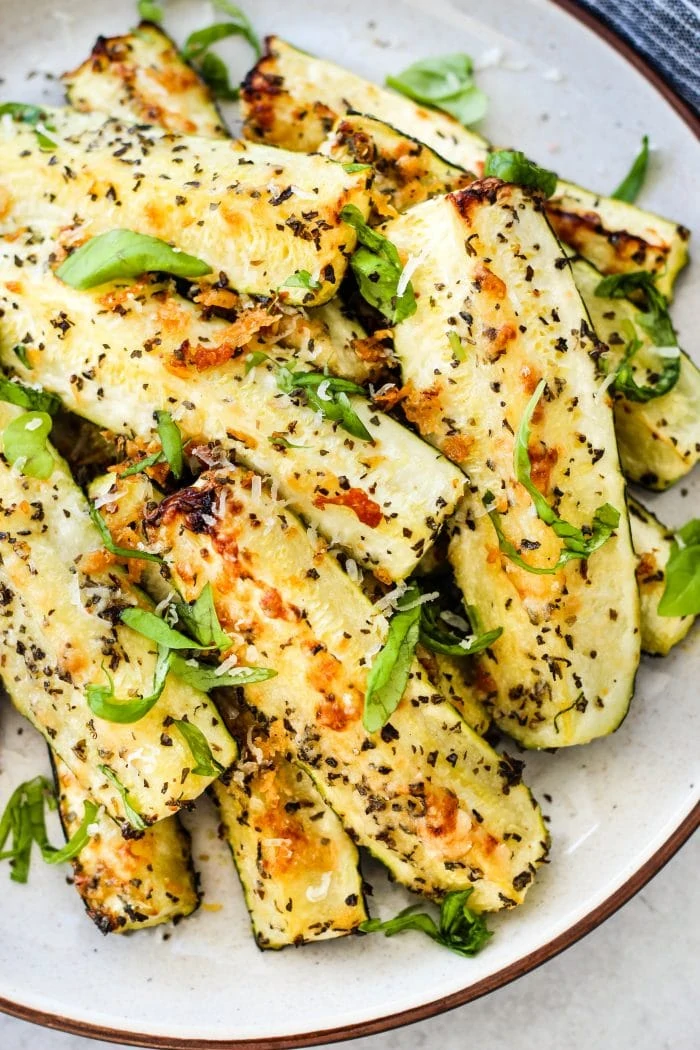 roasted zucchini with parmesan and basil on white plate