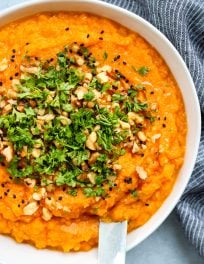miso mashed sweet potatoes in white bowl topped with walnuts and parsley
