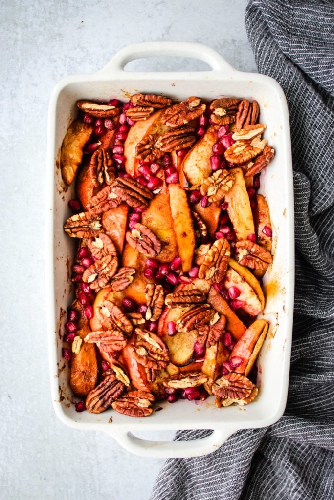 apple, pear, pomegranate and pecan fruit bake in white baking dish