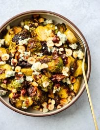 honey and garlic roasted brussels sprouts topped with blue cheese and hazelnuts in a bowl