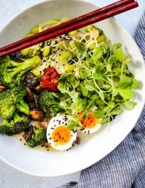 homemade miso ramen noodle soup with broccoli, mushrooms, eggs, and microgreens in white bowl