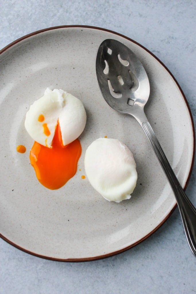 poached eggs with runny yolk on plate with slotted spoon