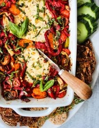 baked feta with peppers and tomatoes in white baking dish