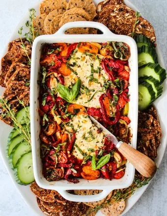 baked feta with peppers and tomatoes in white baking dish