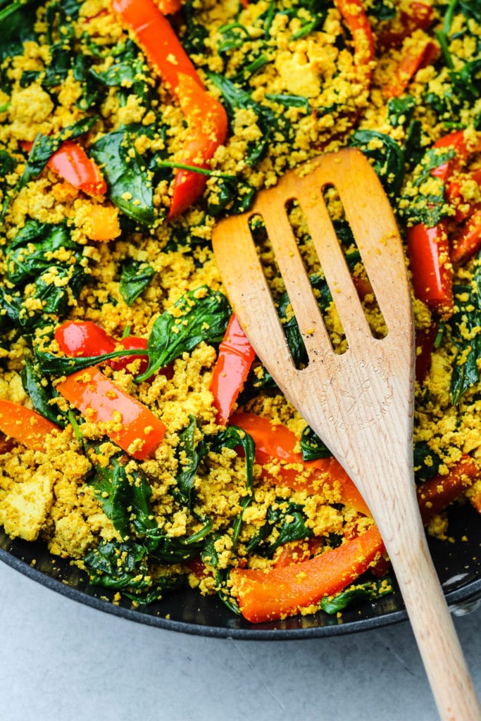 curry tofu scramble with red bell peppers and spinach in a pan