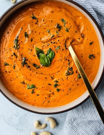 bowl of vegan cashew cream tomato soup with gold spoon