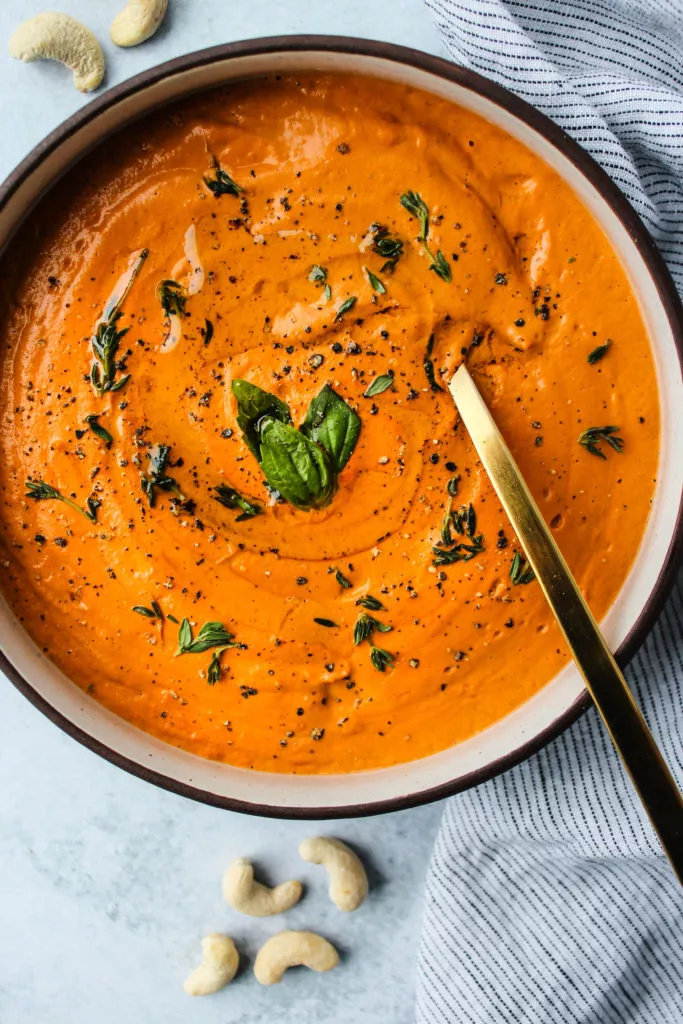 bowl of vegan cashew cream tomato soup with gold spoon