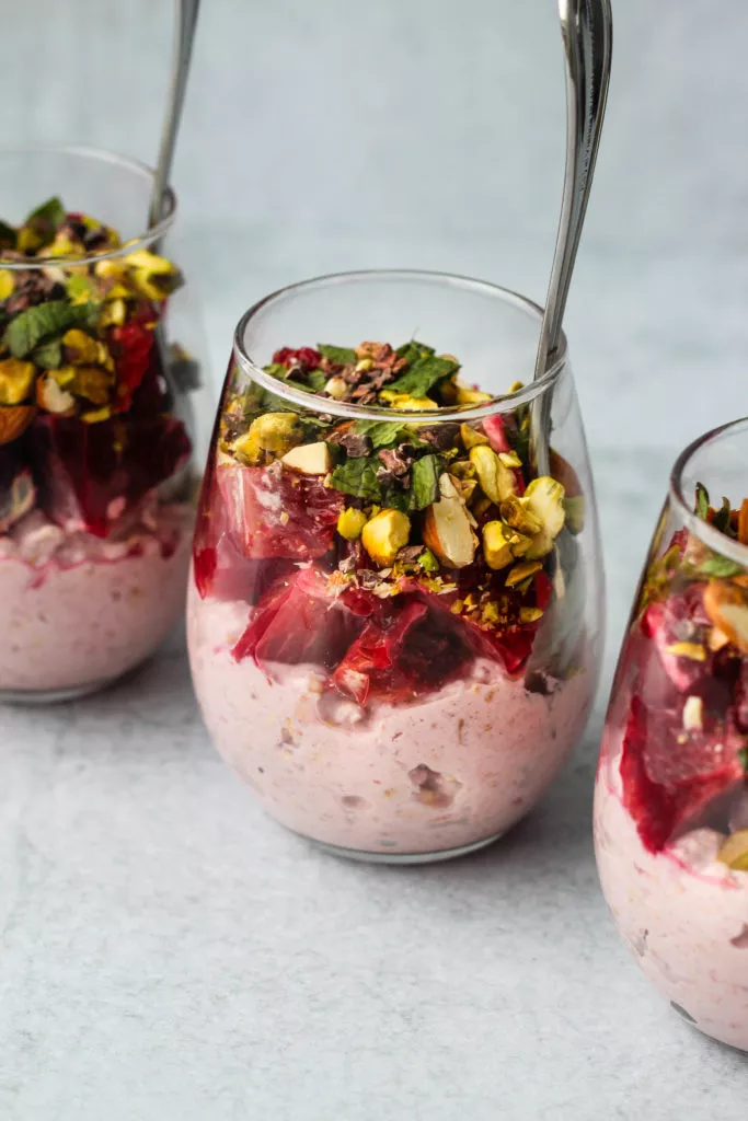 three glass jars of bircher muesli topped with blood orange and nuts