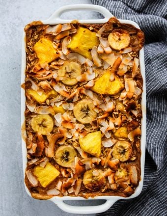 overhead shot of white baking dish with pineapple, banana, and coconut baked oatmeal