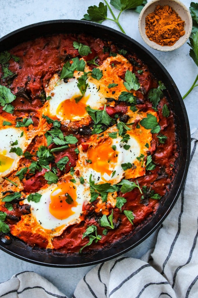 overhead shot of coconut curry shakshuka with runny yolks in a black skillet