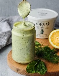spoon dipping into glass jar with herbed siggis yogurt salad dressing