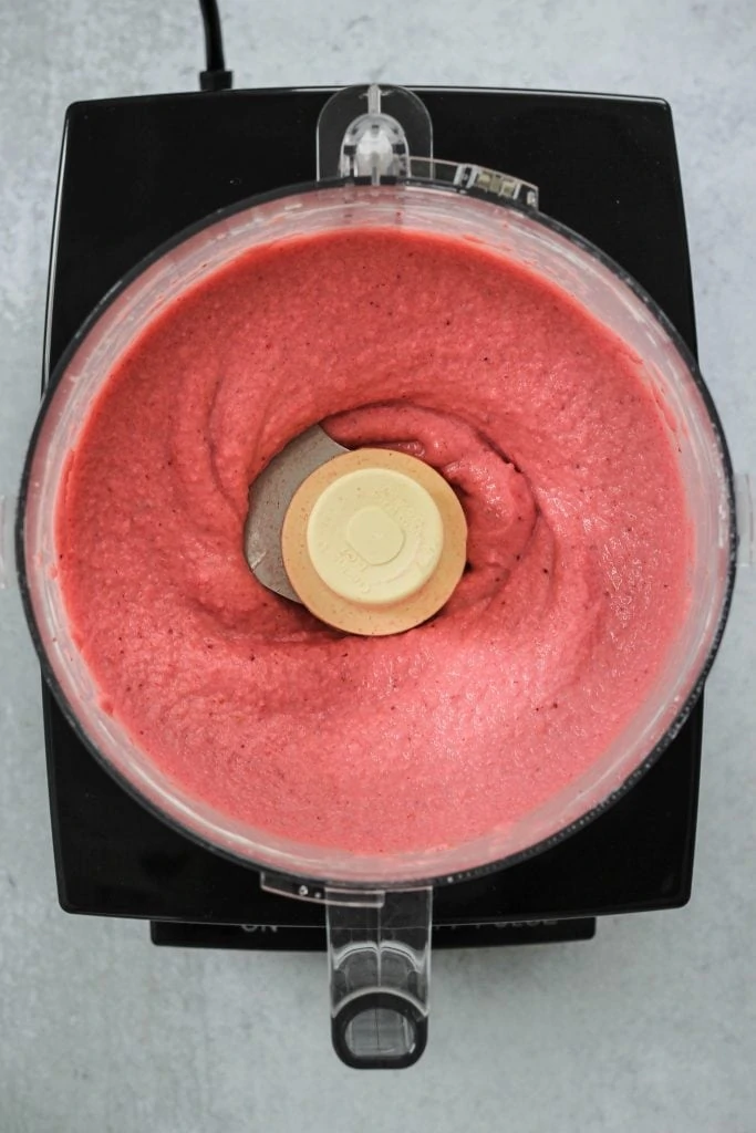 Overhead shot of a food processor with blended strawberries greek yogurt.