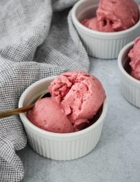 three white ramekins with scoops of homemade strawberry frozen yogurt and blue towel
