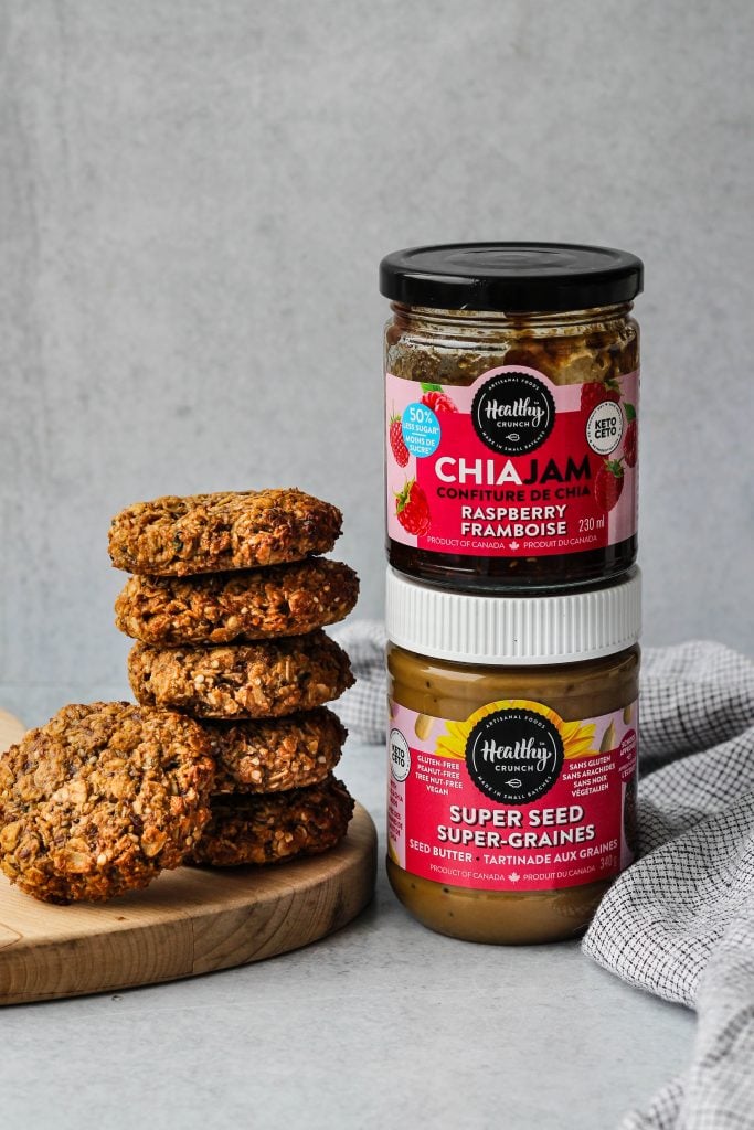 oatmeal cookies stacked next to healthy crunch sunseed butter and chia jam