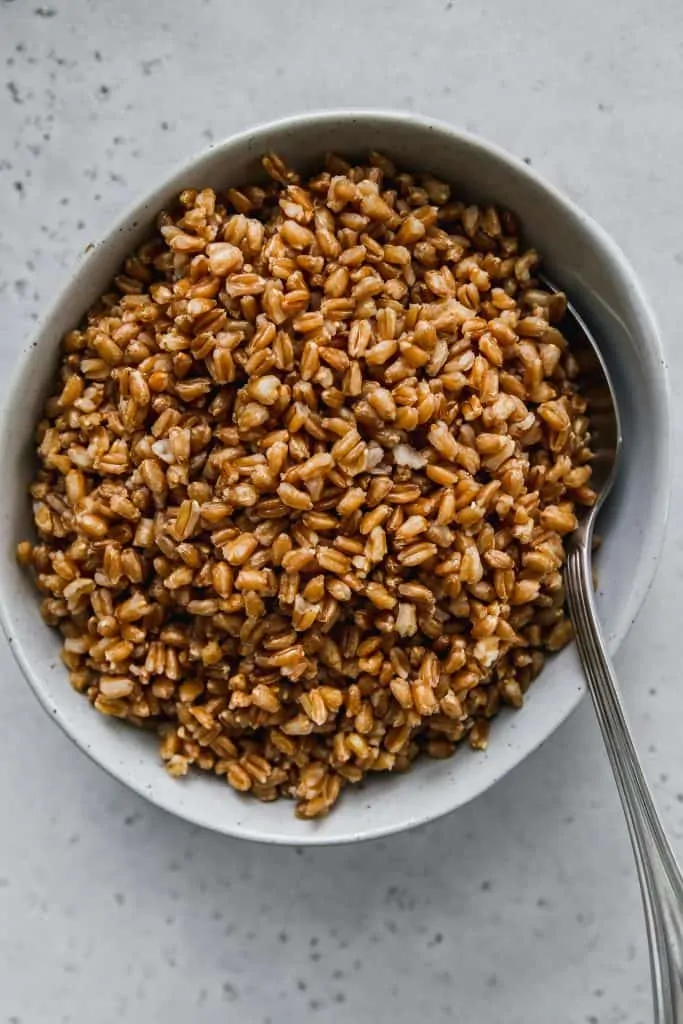 overhead shot of cooked farro in a light blue bowl and a silver spoon
