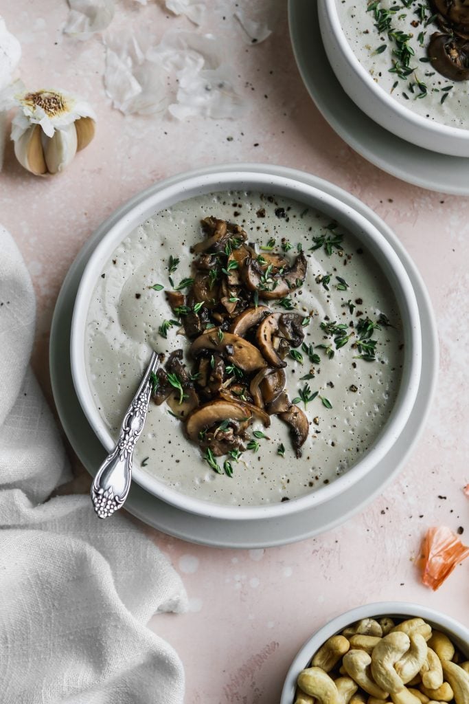 overhead photo of white bowl of vegan cream of mushroom soup with cashews and garlic