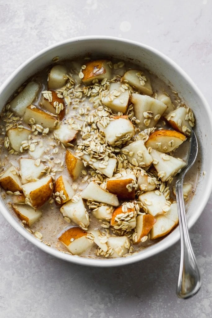 large white mixing bowl with oats and chopped pears