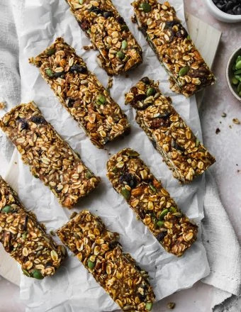 overhead photo of 8 homemade no-bake trail mix granola bars on a wood cutting board with white parchment on top