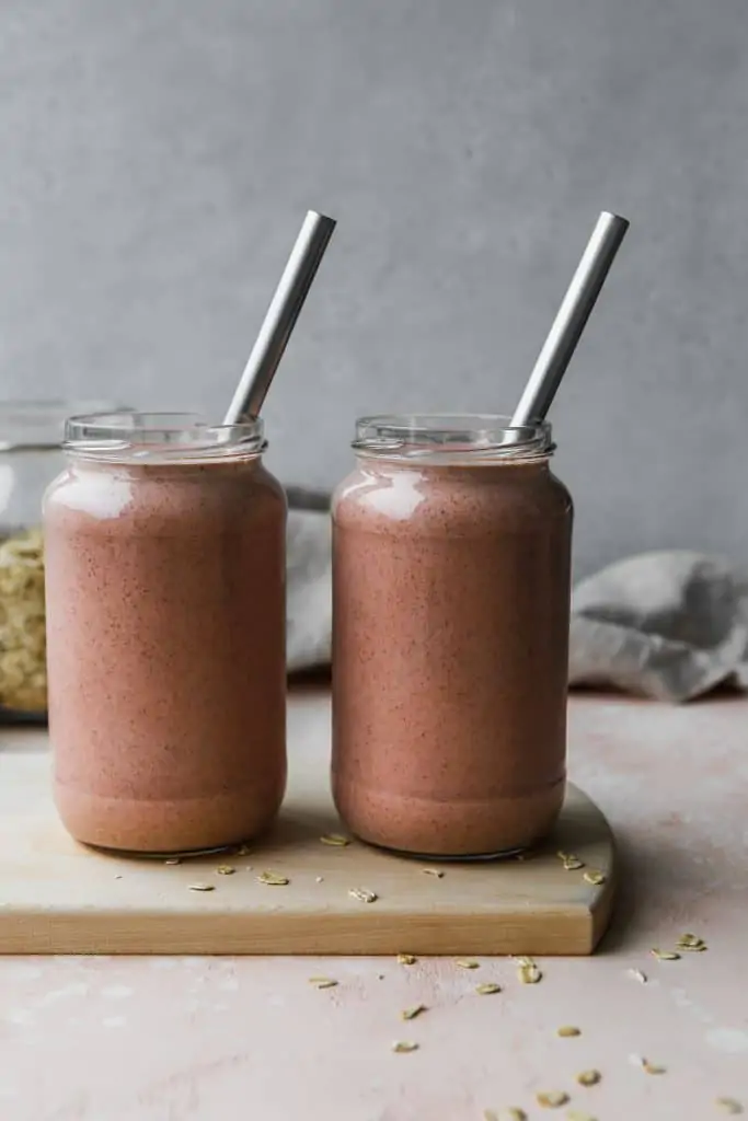 straight on photo of two glass jars of oatmeal smoothie on a wood cutting board