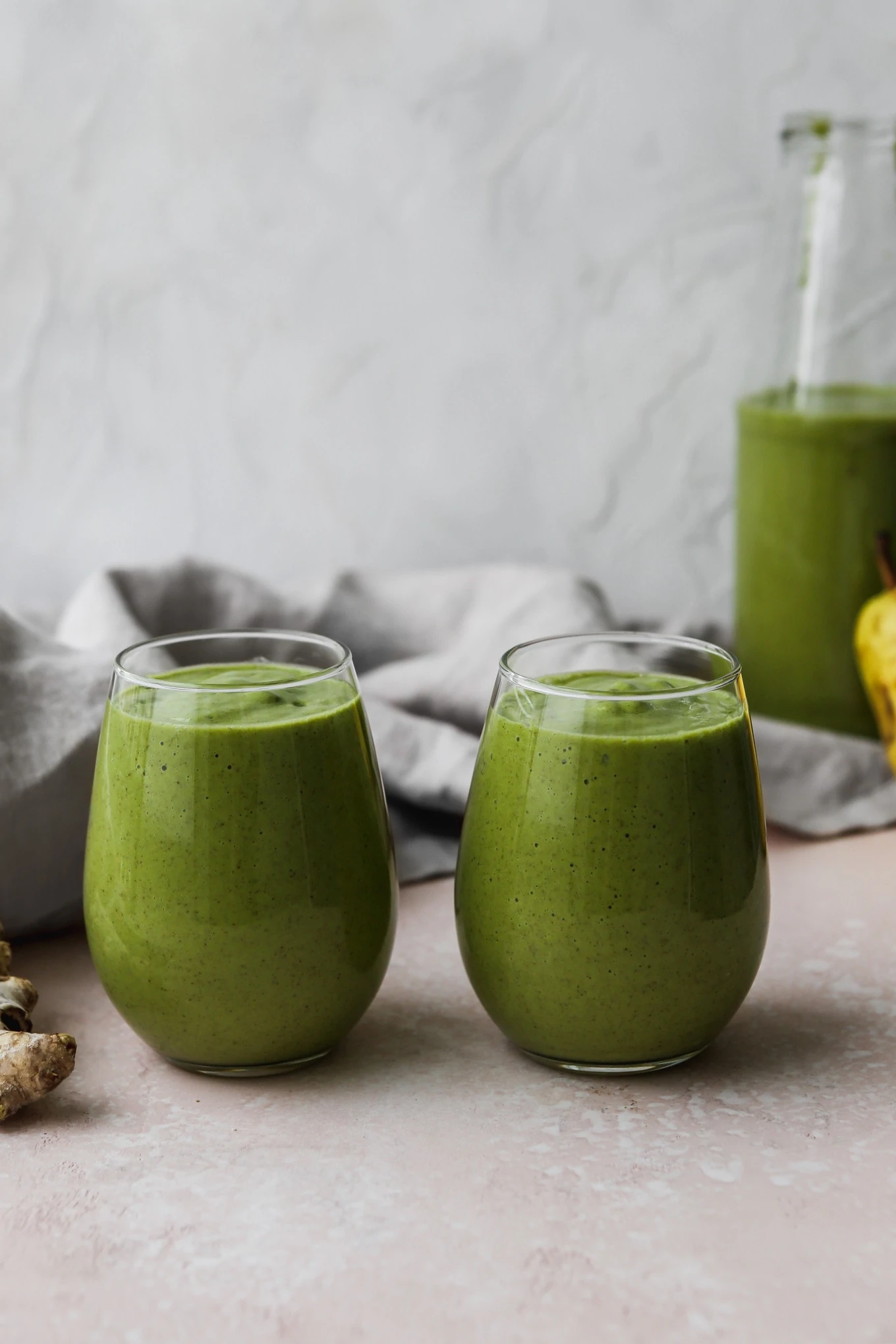 Straight on photograph of two small glasses filled with a pear green smoothie.