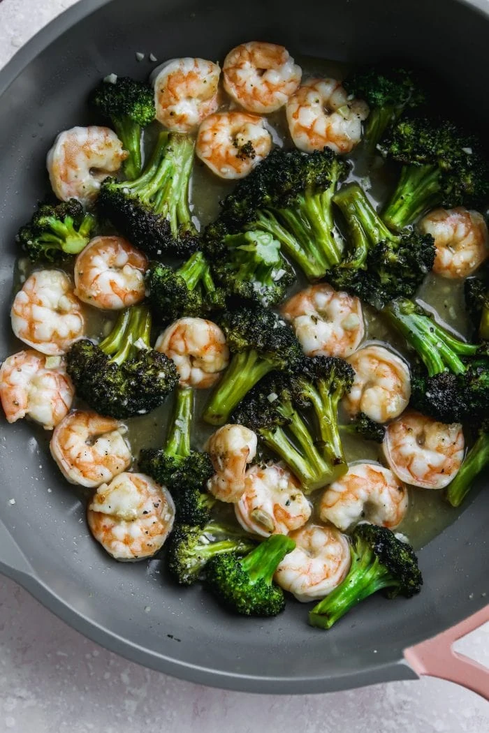 Overhead closeup photo of a grey pan with sautéed shrimp and broccoli inside.
