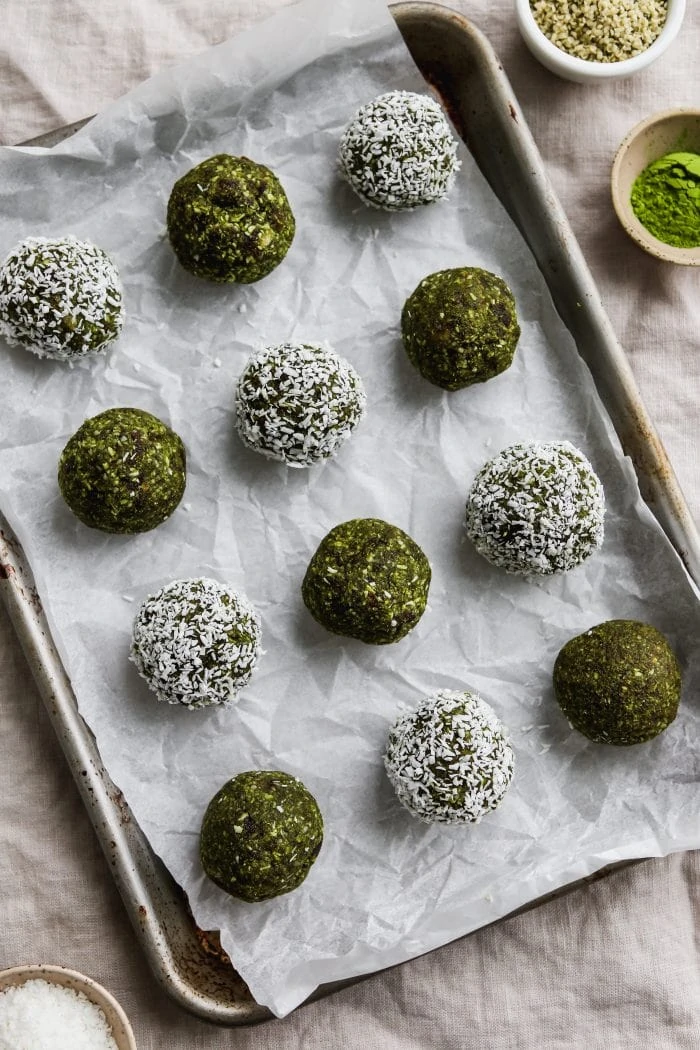 Overhead photo of 12 matcha energy balls on top of a parchment lined baking sheet.