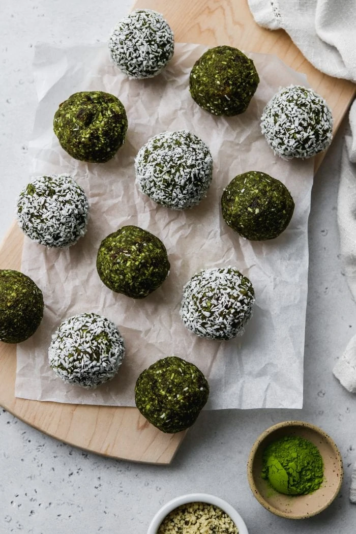 Overhead photo of 12 matcha energy balls on top of a wooden cutting board.