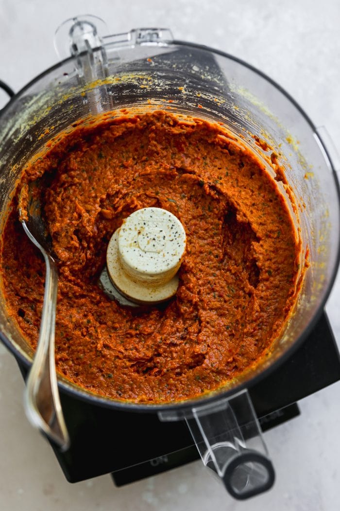Overhead photo of a red pesto sauce mixed in a large food processor.