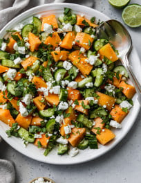 Overhead photo of a cantaloupe cucumber and feta salad on a large white serving plate.