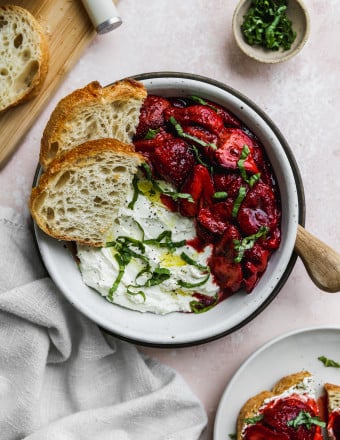 Overhead photo of a white bowl filled with whipped feta, roasted balsamic strawberries, and slices of toast.