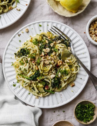 Overhead photo of a white plate topped with lemon artichoke and spinach pasta.