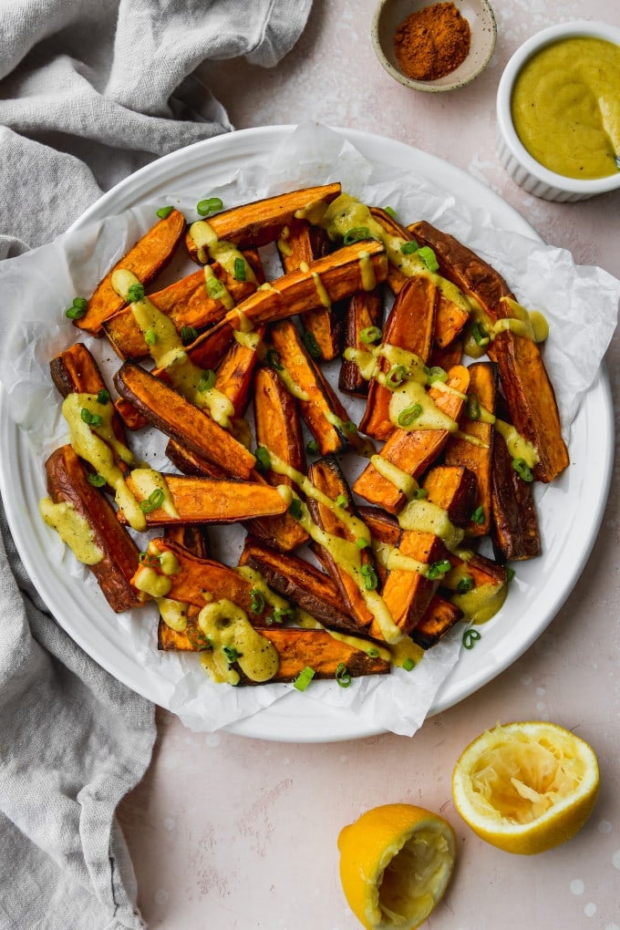 Overhead photo of roasted sweet potato wedges with curry tahini dressing drizzled on top.
