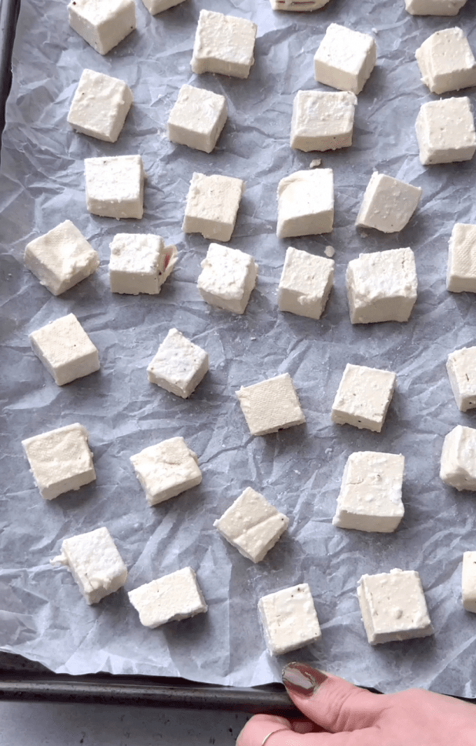 Tofu cubes coated in oil and cornstarch on a baking sheet before going in oven.