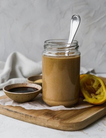 Straight on photo of a small glass jar filled with balsamic tahini dressing.