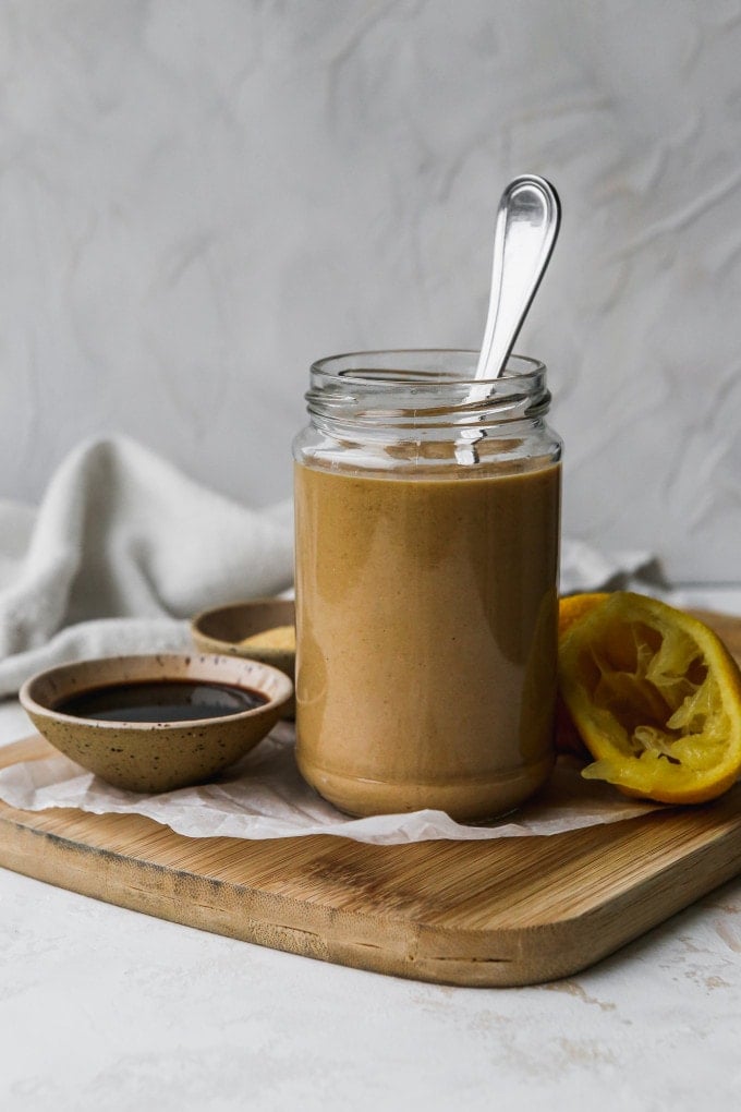 Straight on photo of a small glass jar filled with balsamic tahini dressing.