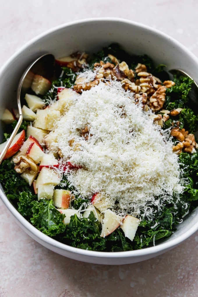 Overhead photo of kale salad ingredients in a large white bowl.