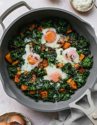 Overhead photo of a kale butternut squash hash with eggs in a pan.