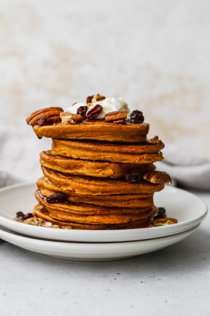 Straight on photo of a stack of butternut squash pancakes on a white plate.