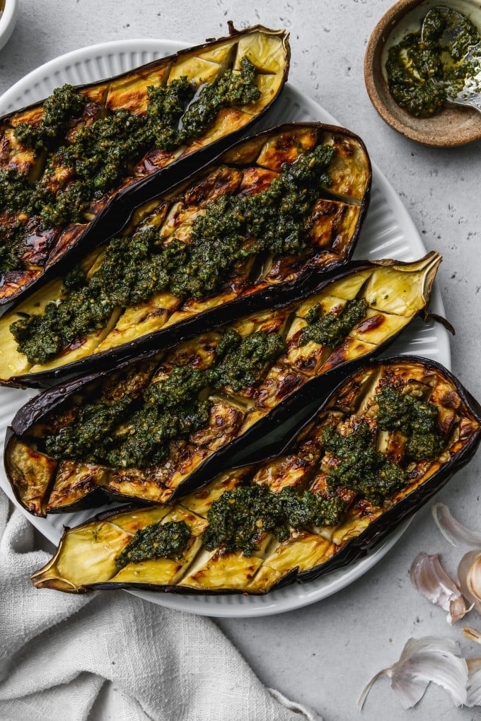 Overhead photo of roasted eggplant with honey and chermoula on a white serving plate.