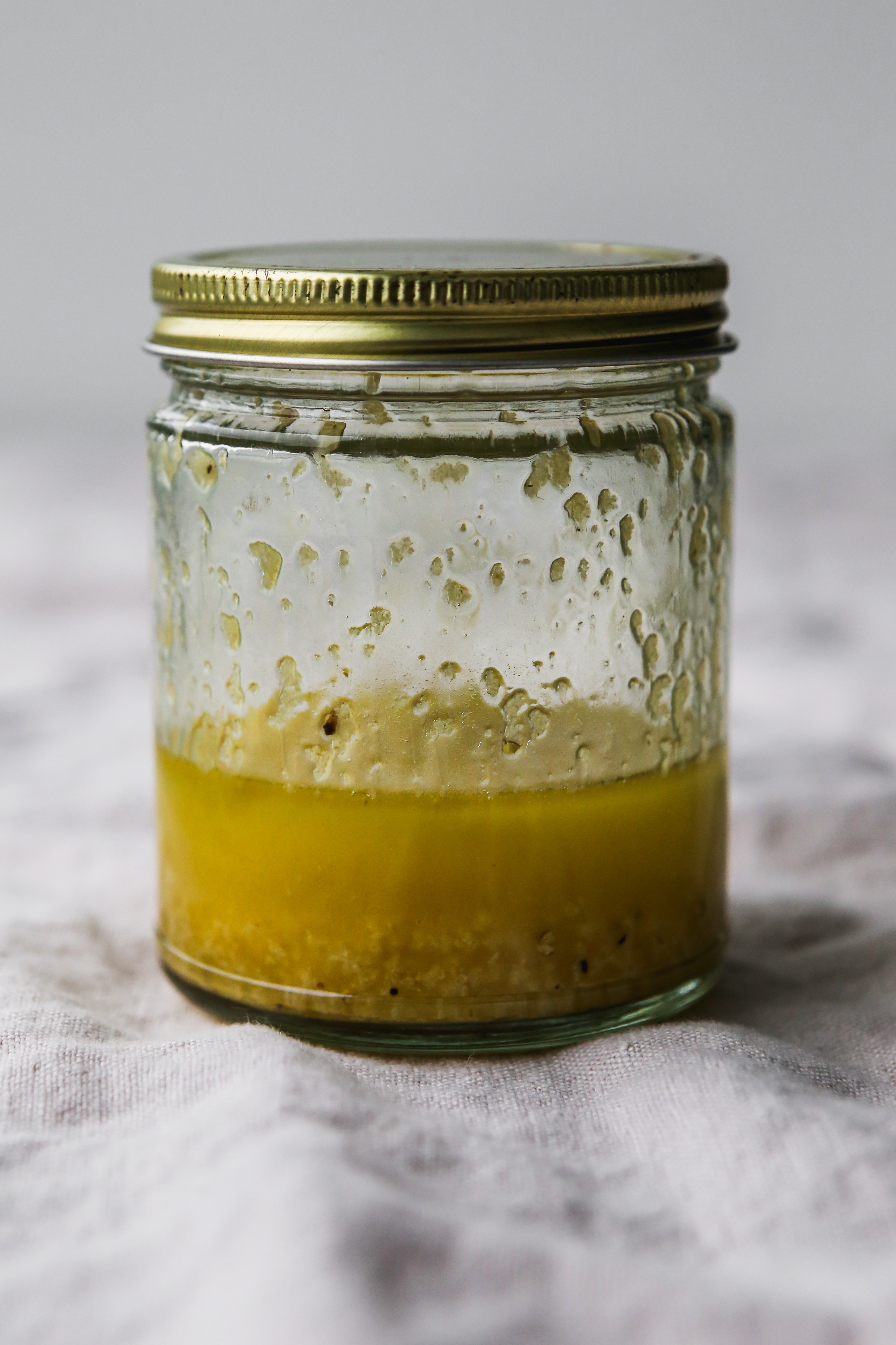Straight on photo of a jar of olive oil, lemon, and garlic dressing shaken together.